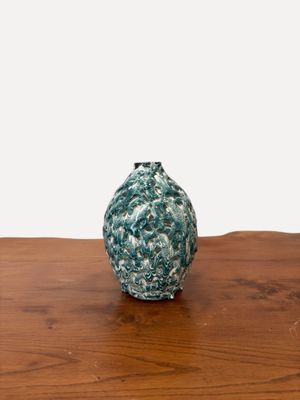 un petit vase vert posé sur une table en bois