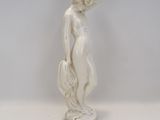 statue d'une femme debout sur un socle, les mains dans les poches