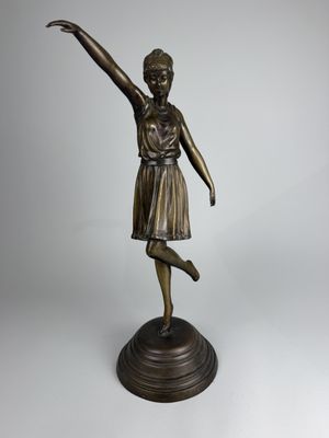 a bronze statue of a woman holding a tennis racquet