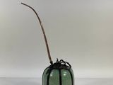 an image of a green vase with a stick sticking out of it