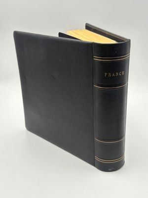 un vieux livre à la couverture noire posé sur une table blanche