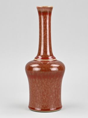 an orange vase sitting on top of a white table next to a white wall