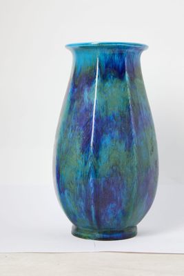 a blue and green vase sitting on a white surface