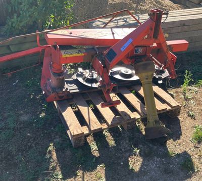 une machine rouge posée sur une palette dans l'herbe