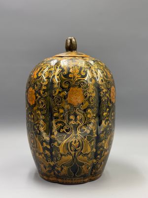 un vase noir et or posé sur une surface blanche