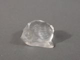une figurine en verre transparent représentant une femme posée sur une surface grise