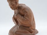 une image représentant la statue d'un homme agenouillé sur une surface blanche