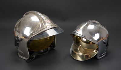 une paire de casques argentés posés sur une surface noire, sur fond noir