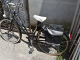 a bicycle parked next to a fence with a bag on it