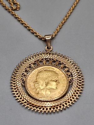 un pendentif en forme de pièce d'or sur lequel est gravé le visage d'une femme