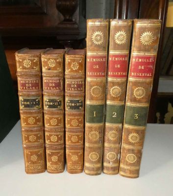 Plusieurs vieux livres sont alignés sur une table devant une horloge