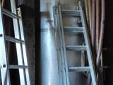 Plusieurs échelles sont appuyées contre un mur dans une pièce.