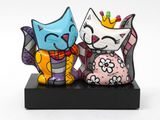 two figurines of cats that are sitting on a stand