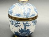 blue and white porcelain jar with a gold lid and a pine tree design
