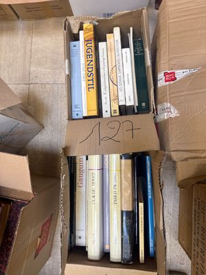 a box full of books sitting on the floor next to a pile of books