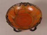 an orange bowl with a black handle on a white table