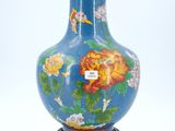 a blue vase with flowers on it sitting on a stand