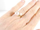 a woman ' s hand with a pearl ring on it