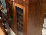 a wooden cabinet with a glass door and a chair in front of it