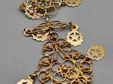 a close up of a gold necklace with a bunch of charms on it