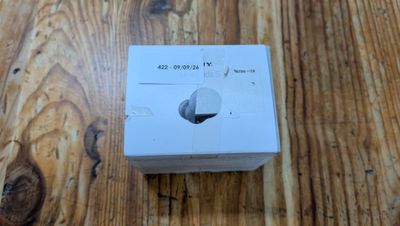 une boîte blanche posée sur une table en bois, sur laquelle se trouve un bouton blanc