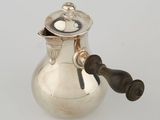 an antique silver coffee pot with a wooden handle on a white surface