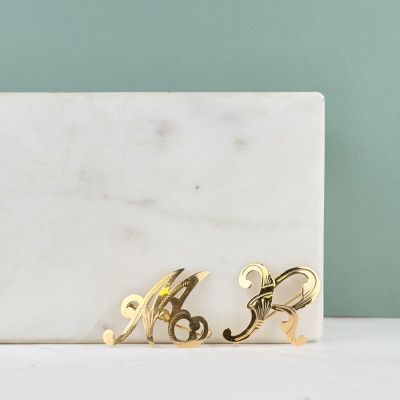 un gros plan sur une paire de boucles d'oreilles en or posées sur une surface en marbre