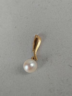 a close up of a pearl pendant on a white surface