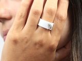 Quelqu'un porte une bague blanche sertie d'un diamant.