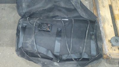 un sac noir posé par terre à côté d'un banc en bois