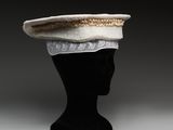 chapeau en tricot blanc et doré posé sur une tête de mannequin noire