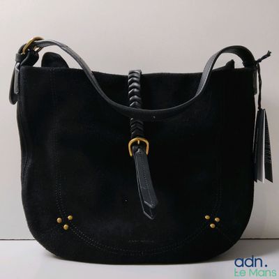 Le sac à main noir est posé sur une surface blanche et est muni d'une poignée noire.