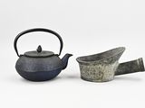 two teapots and a watering can on a white surface