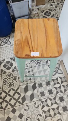 a wooden stool sitting on a tiled floor in a kitchen