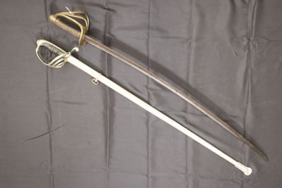 une vieille épée avec une poignée en bois posée sur un tissu noir