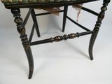 une chaise noire avec une assise verte et une plume posée dessus