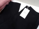 black pants with a tag on a hanger on a white table