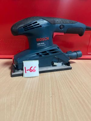 une ponceuse orbitale Bosch posée sur une table, à côté d'une boîte rouge