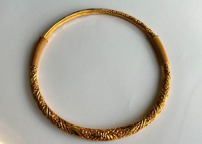 une image d'un bracelet en or sur une surface blanche