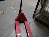 un chariot élévateur rouge posé au sol dans un entrepôt