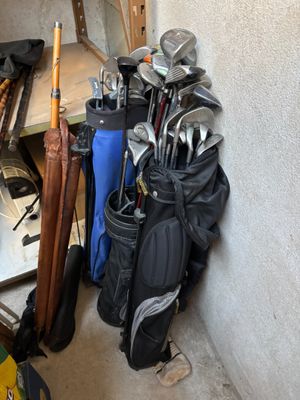 Plusieurs clubs de golf sont alignés contre un mur dans un garage