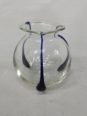 un vase en verre avec une anse bleue posé sur une table