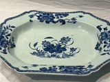 an old blue and white plate with flowers on it on a table