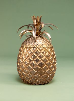 a gold pineapple sitting on a green surface