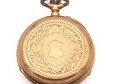 a gold pocket watch with a picture of an apple on it