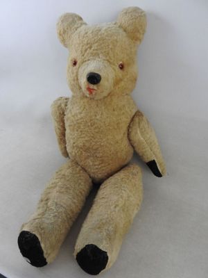 un ours en peluche assis sur une surface blanche