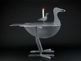 two birds that are sitting on a table with a candle