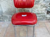 a red chair that is sitting in front of a stone wall