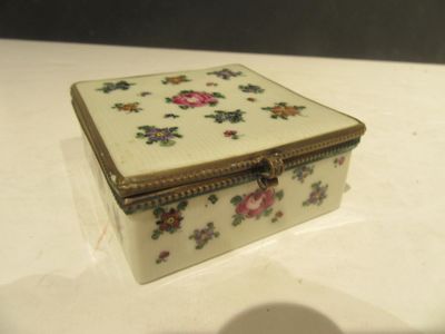 une petite boîte blanche décorée de fleurs, posée sur une table