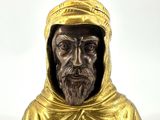 statue d'un homme vêtu d'une robe dorée et coiffé d'un chapeau doré